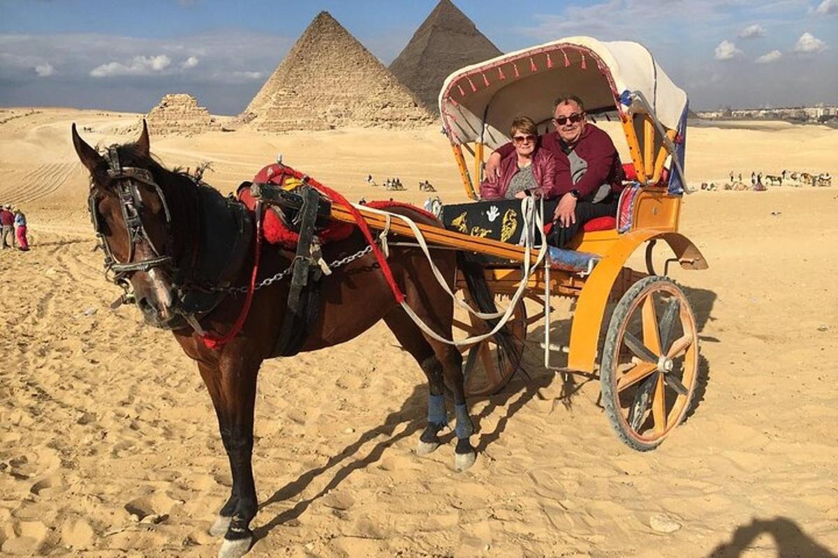 due persone in carrozza trainata da cavalli davanti alle piramidi
