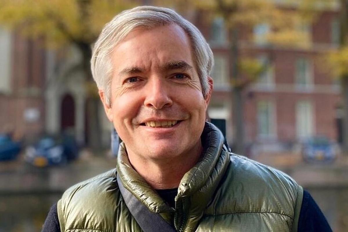 a man in a green jacket smiles at the camera