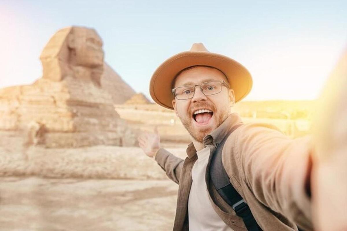 en mann i hatt som står foran pyramidene