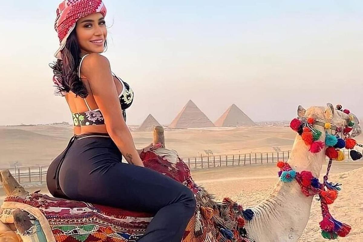 una donna seduta su un cammello davanti alle piramidi