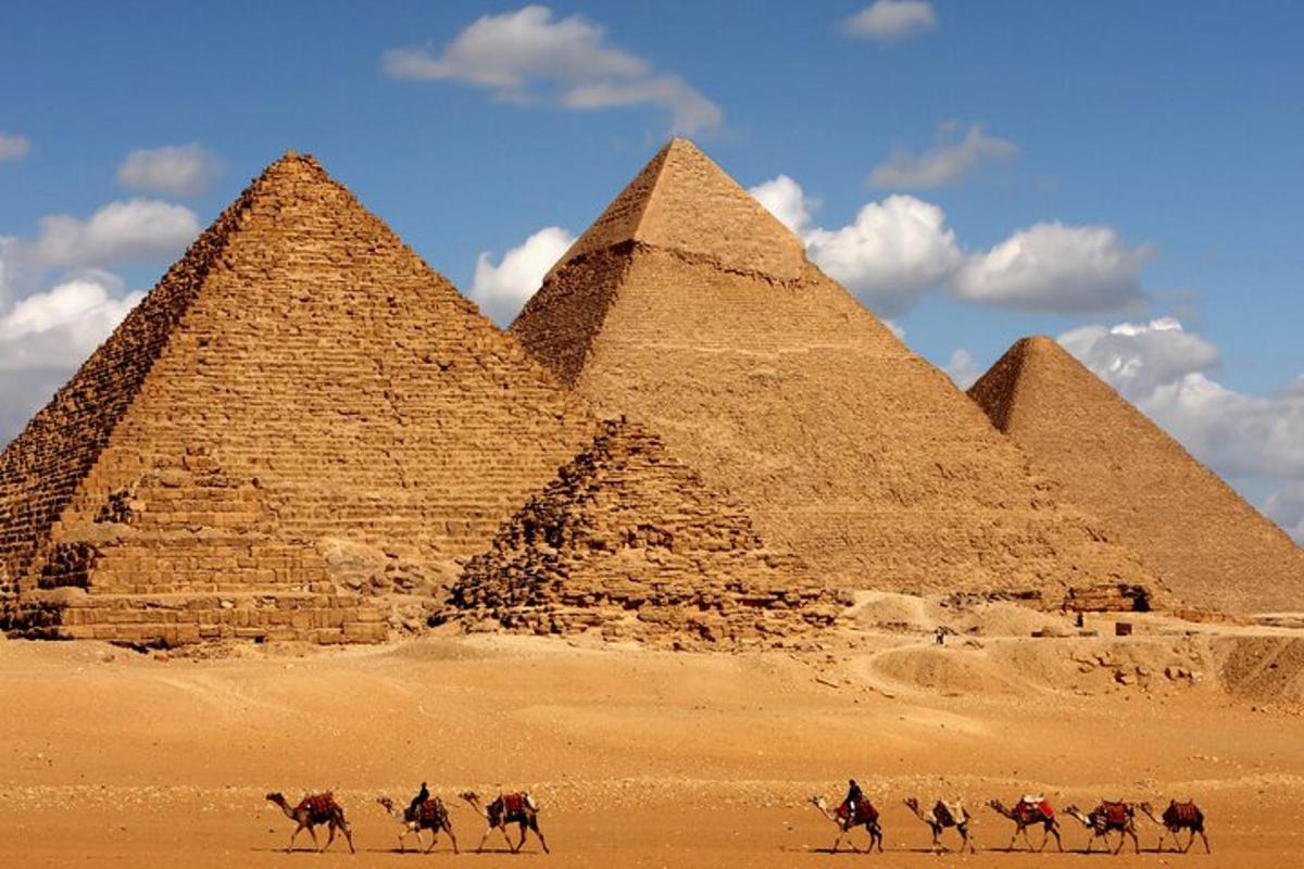 Skupina lidí na koních před pyramidami