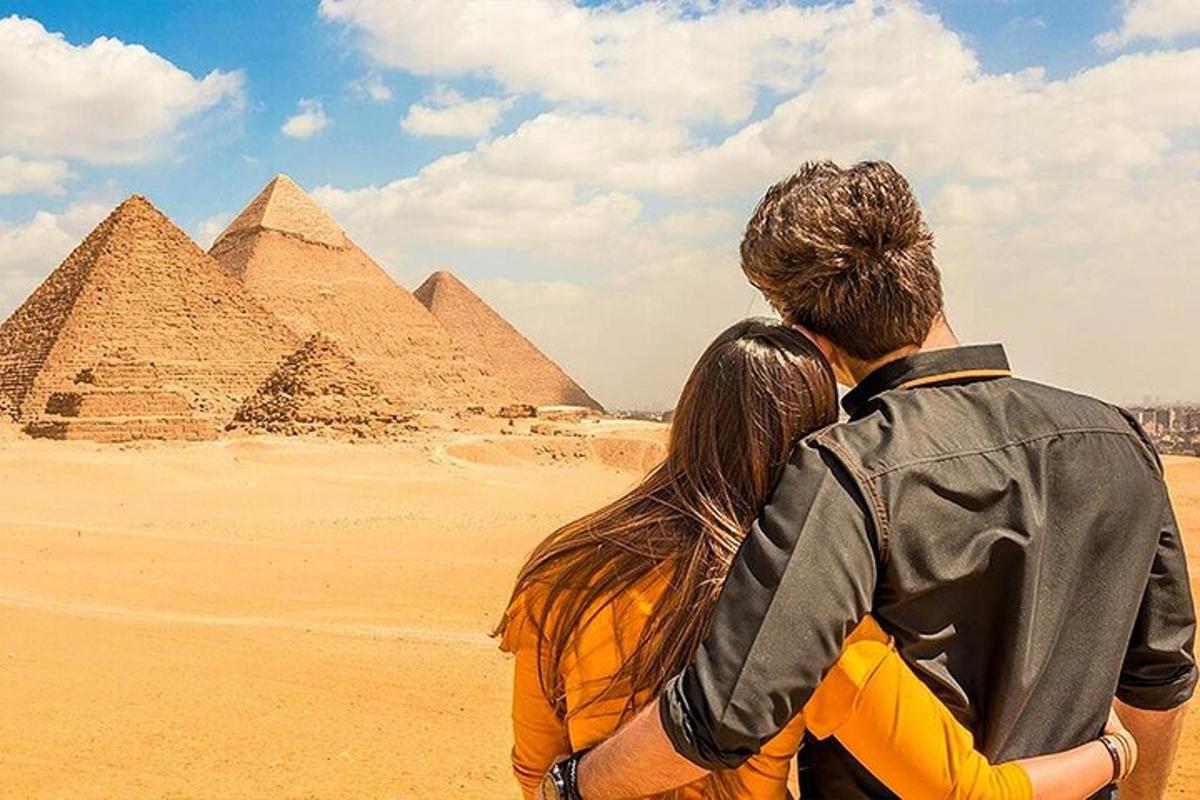 Un hombre y una mujer de pie frente a las pirámides.