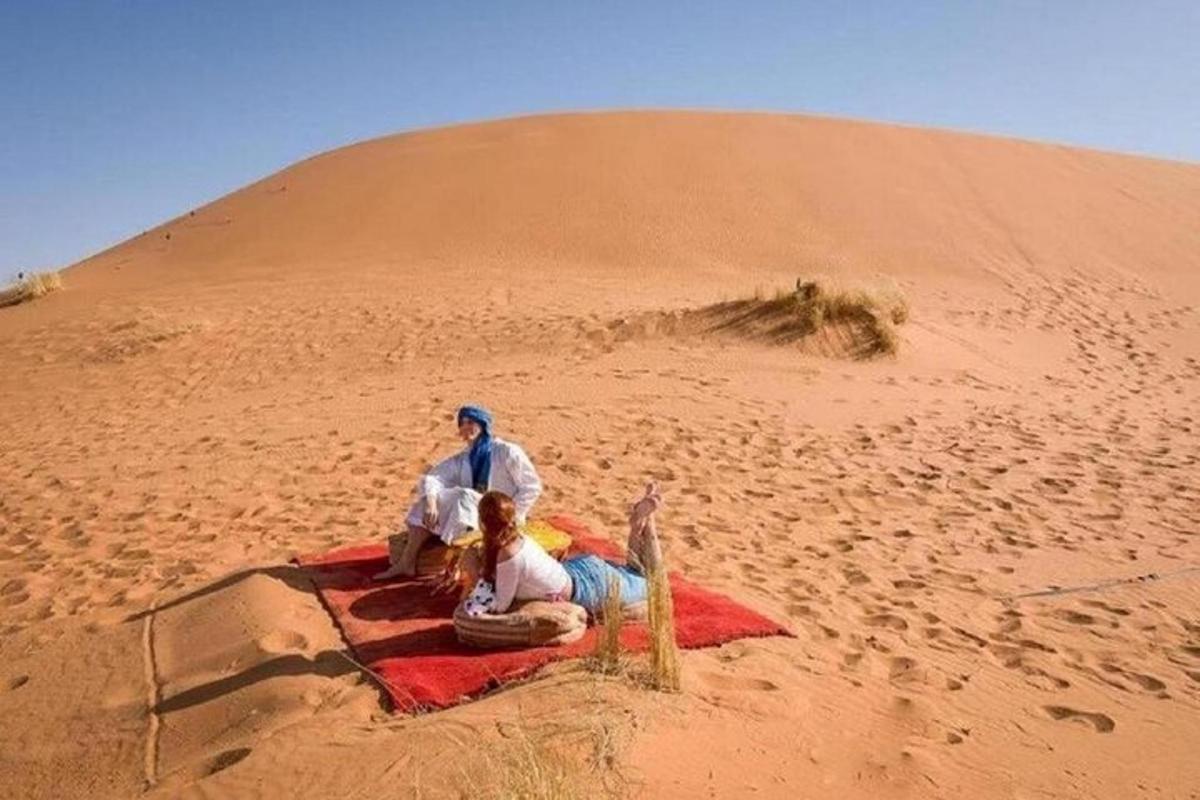 two people sitting on a blanket in the desert