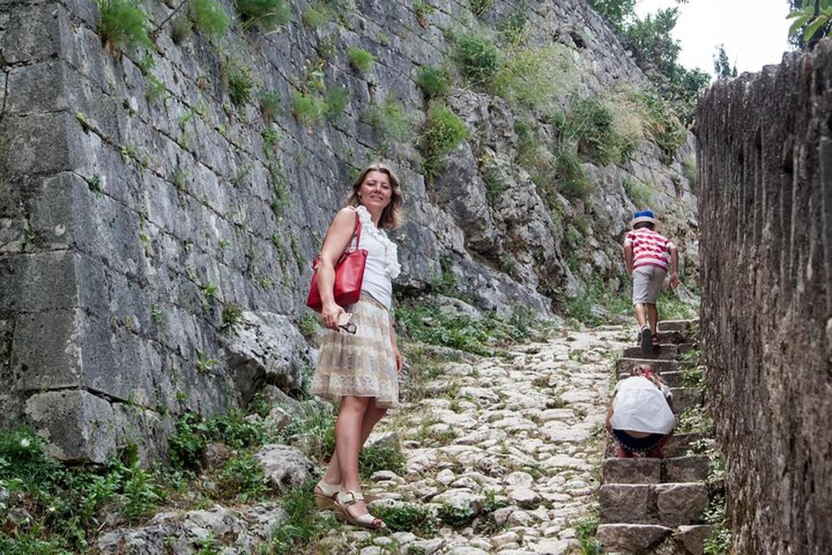 ženska, ki stoji na skalnati poti ob zidu