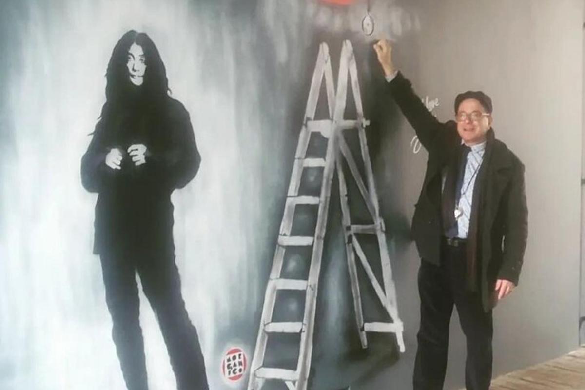 un uomo in piedi davanti a un muro con una scala
