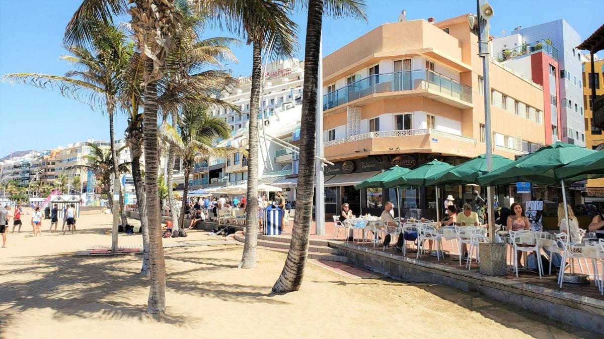 folk som sitter ved bord på en strand med palmer