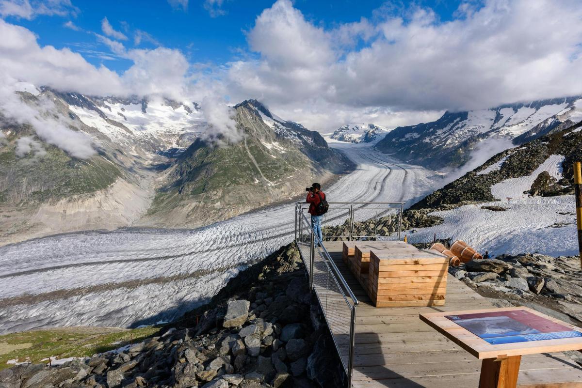 a person standing on a viewing platform on a mountain
