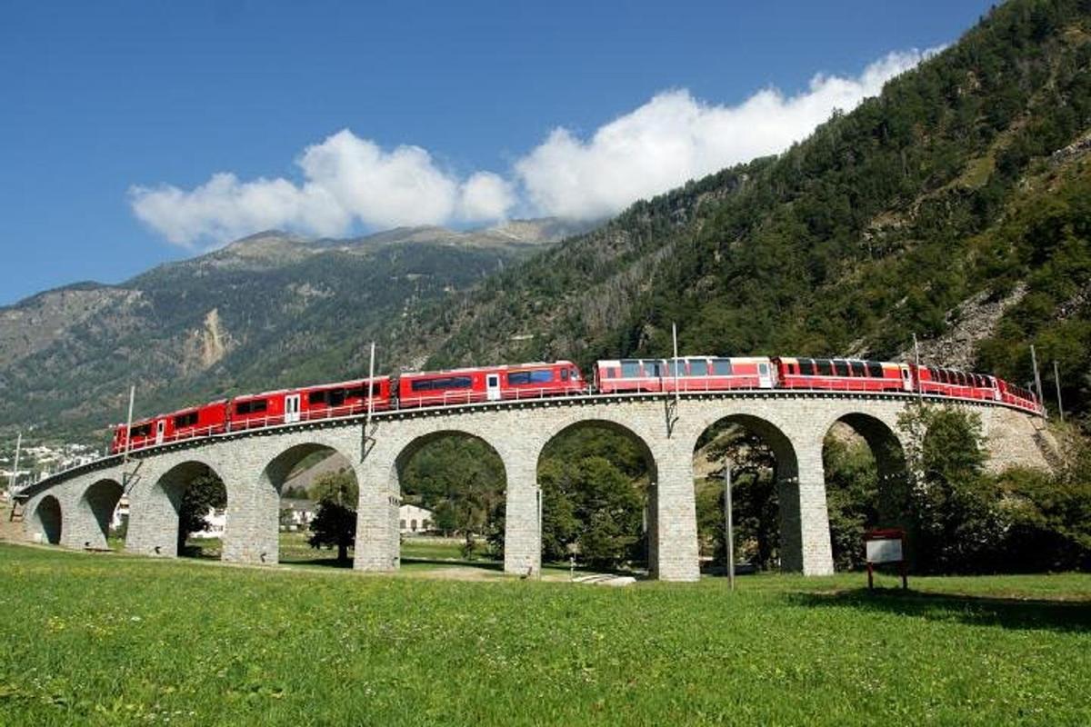 un treno rosso su un ponte sopra una montagna
