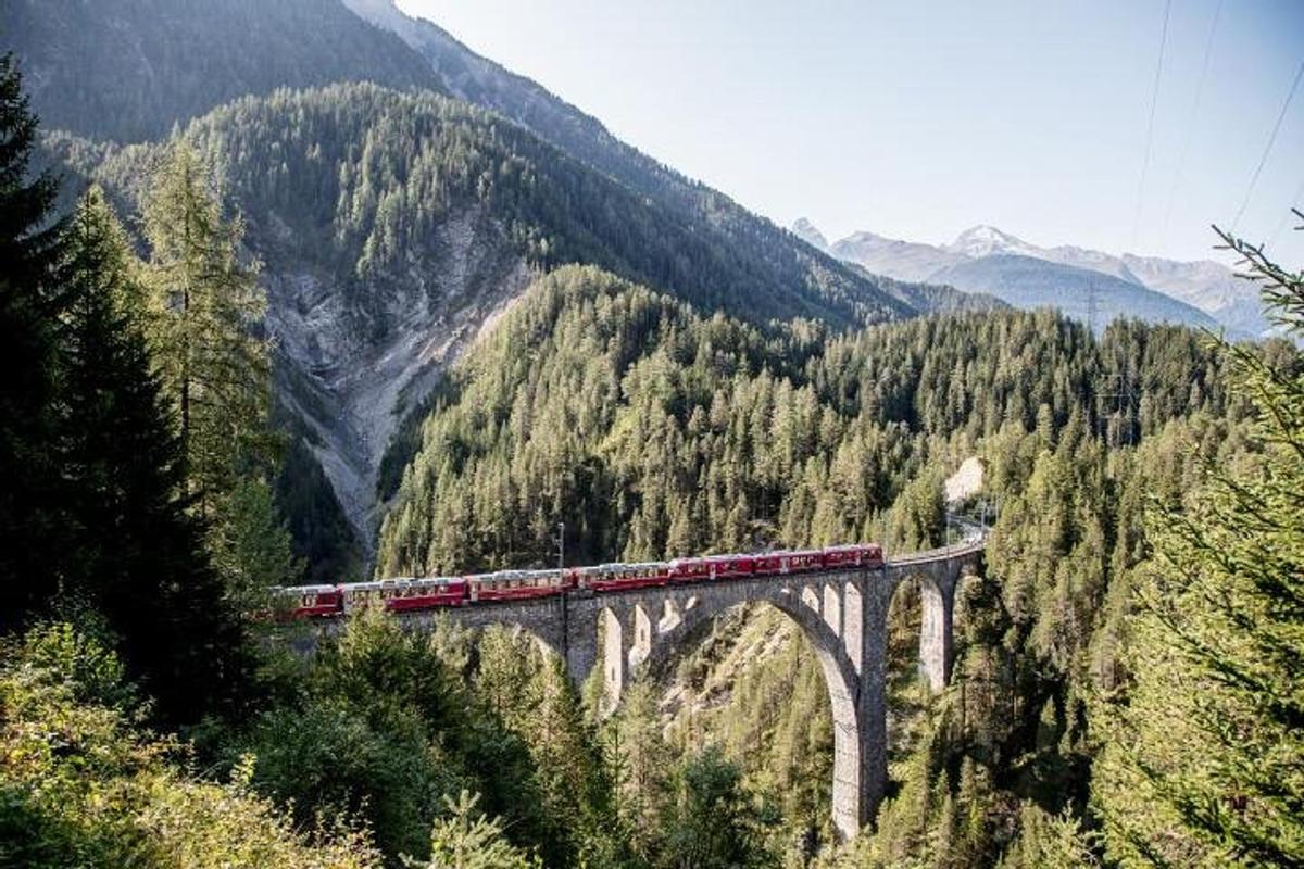 a train on a bridge in the mountains