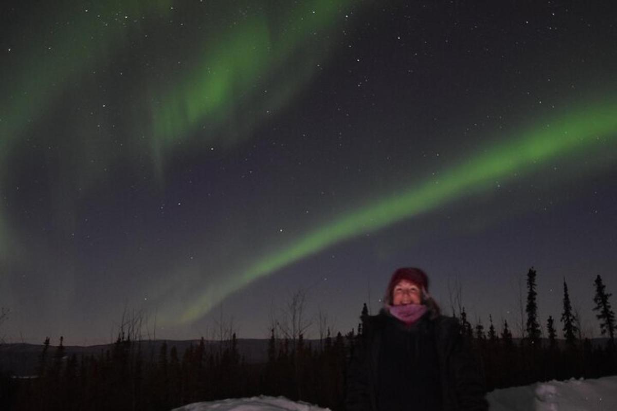 Kona stendur undir norðurljósunum