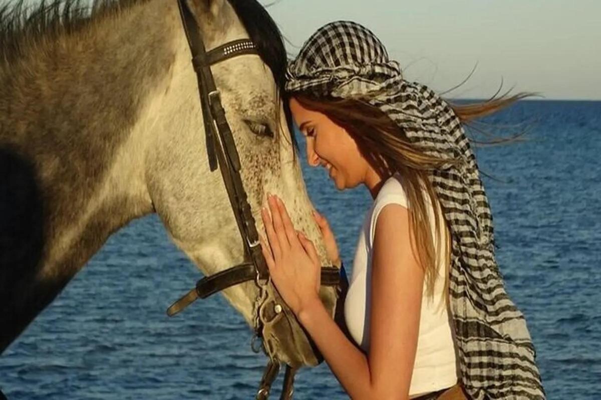 μια γυναίκα στέκεται δίπλα σε ένα άλογο