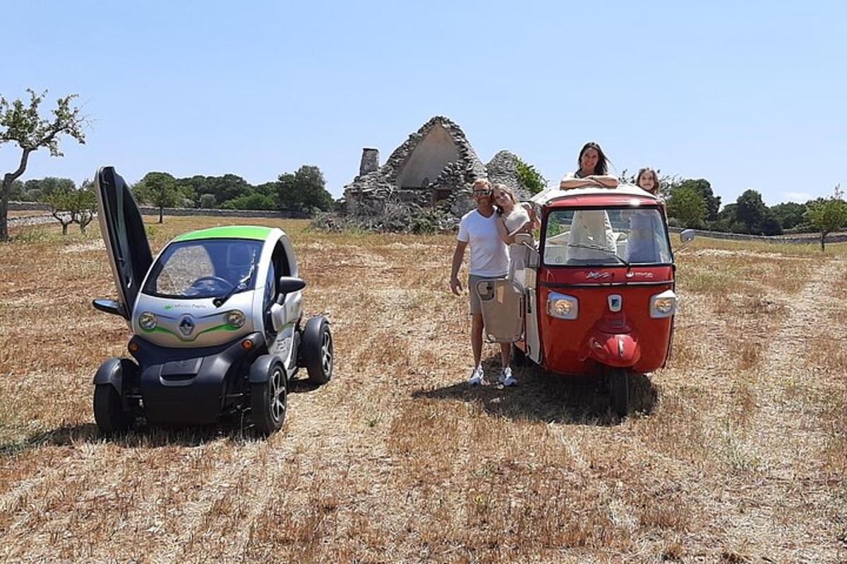 Dos personas de pie junto a un coche y un carrito de golf.