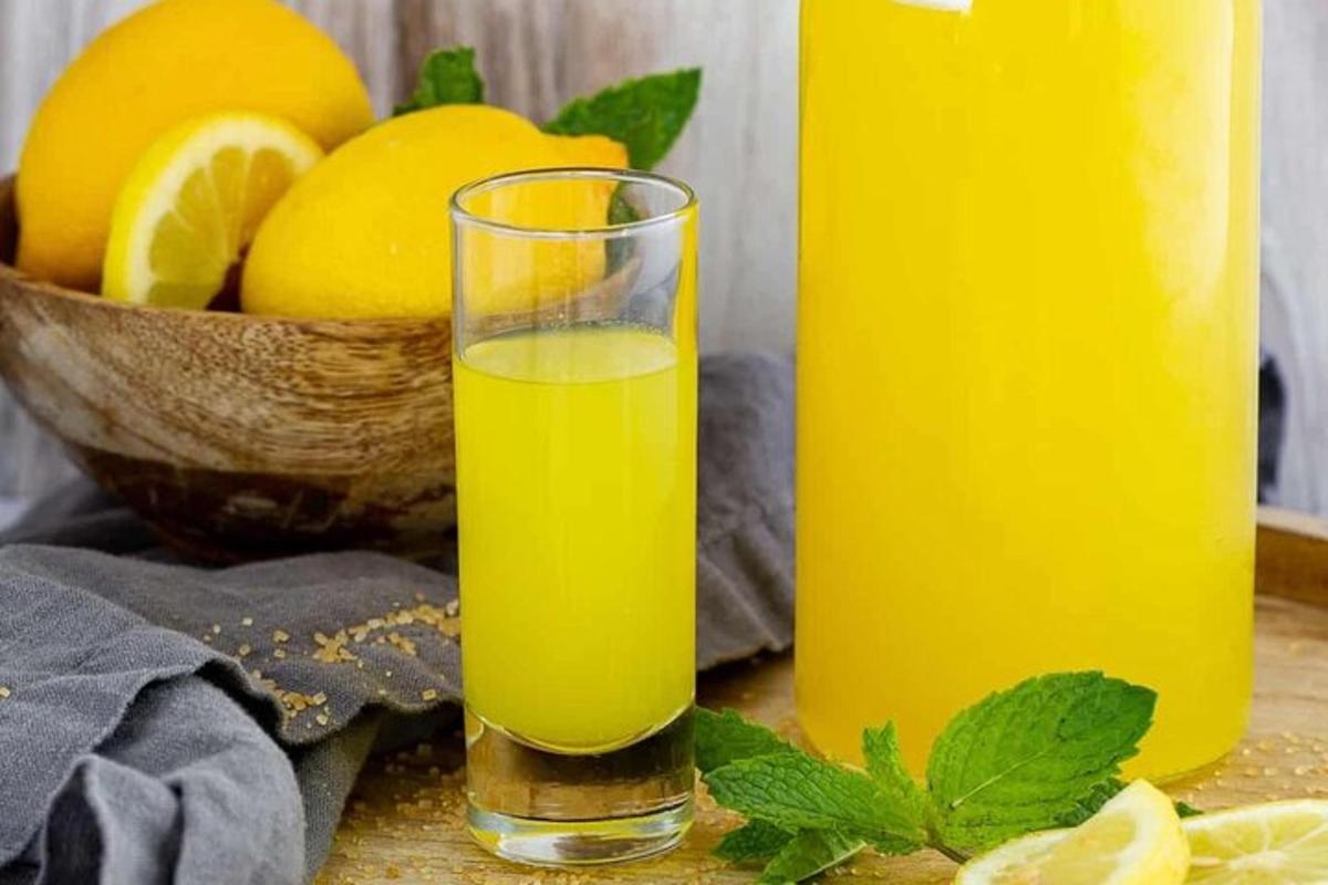 sklenice pomerančové šťávy vedle misky citronů