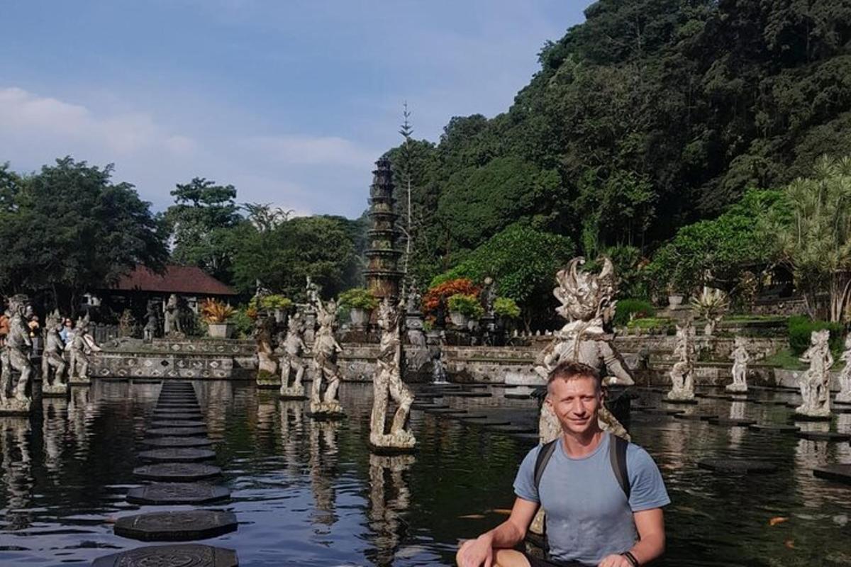 seorang lelaki duduk di dalam air di hadapan sebuah kuil
