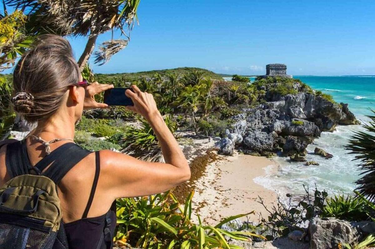 Una mujer tomando una fotografía de una playa con una cámara.