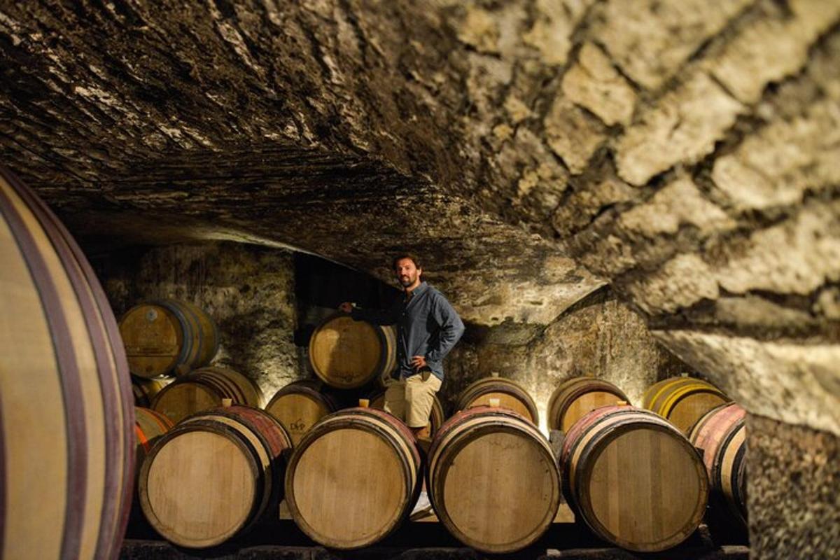 un uomo in piedi accanto a un mucchio di barili in una grotta