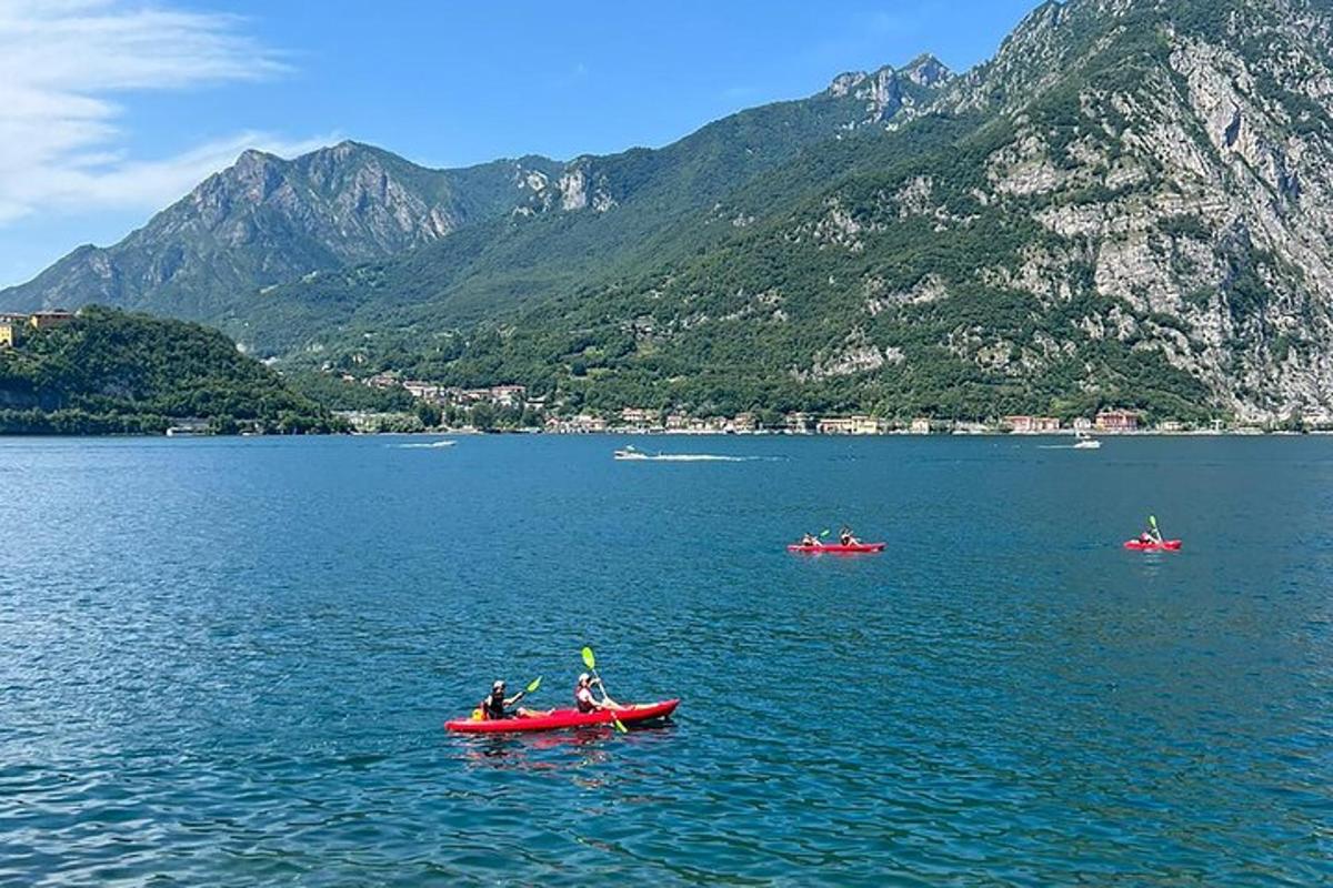 ba người chèo thuyền kayak màu đỏ trên một hồ nước có núi