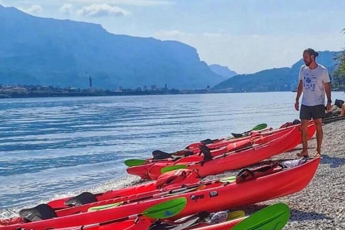 một người đàn ông đứng cạnh một hàng thuyền kayak trên bãi biển