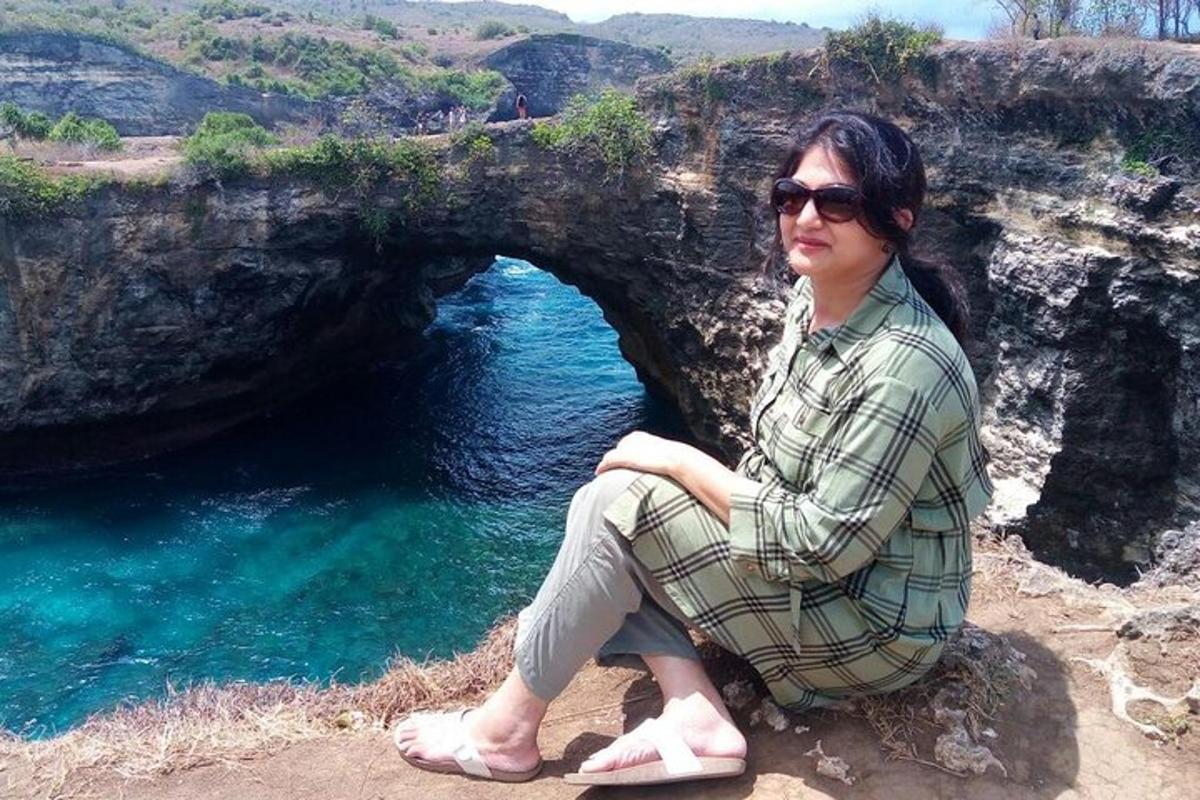 a woman sitting on a rock in front of a cave