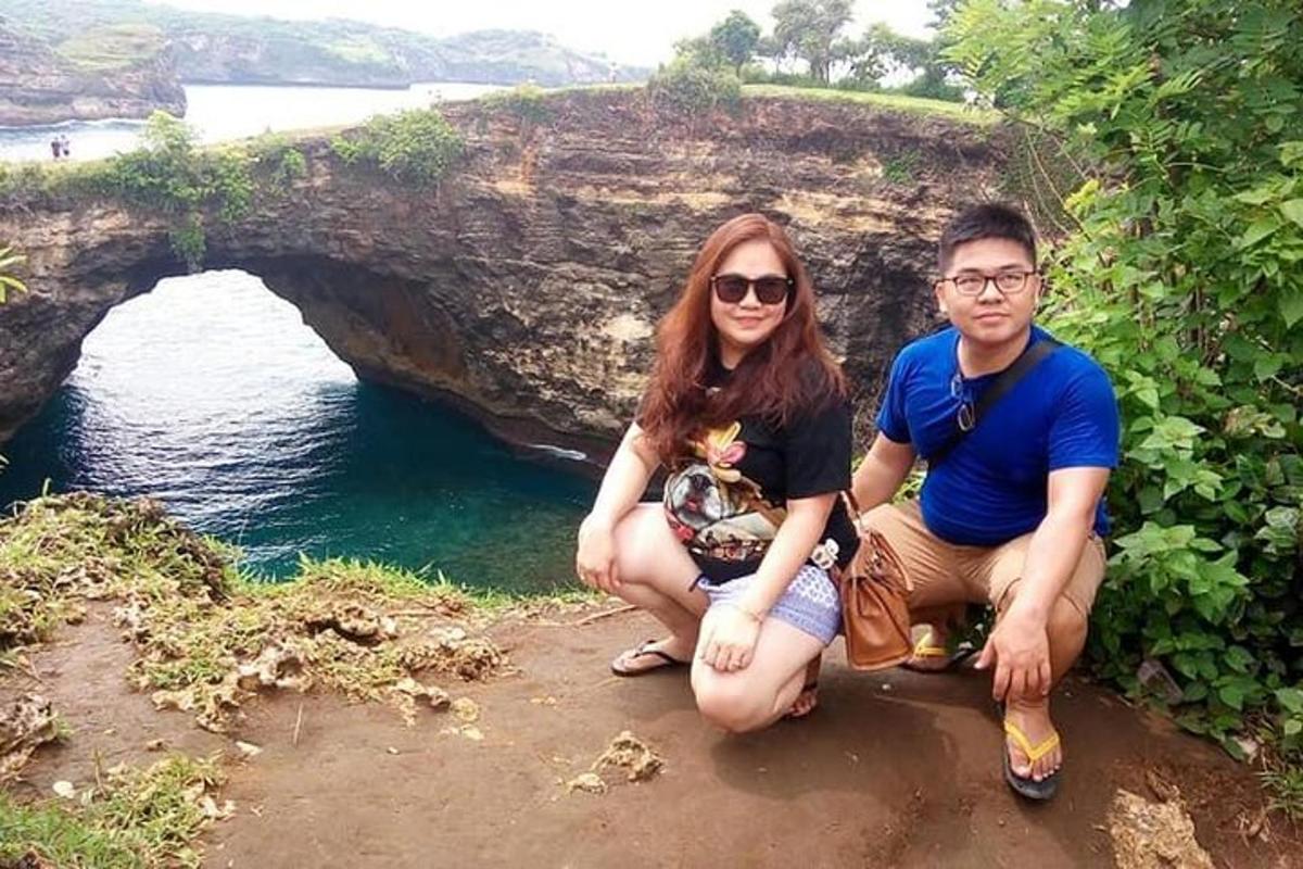 a man and a woman sitting on a rock near the water