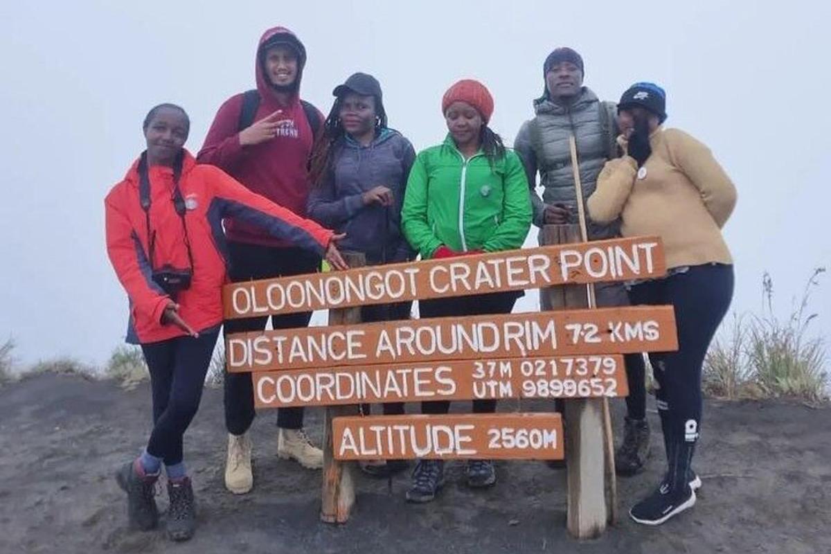 un gruppo di persone in piedi accanto a un cartello