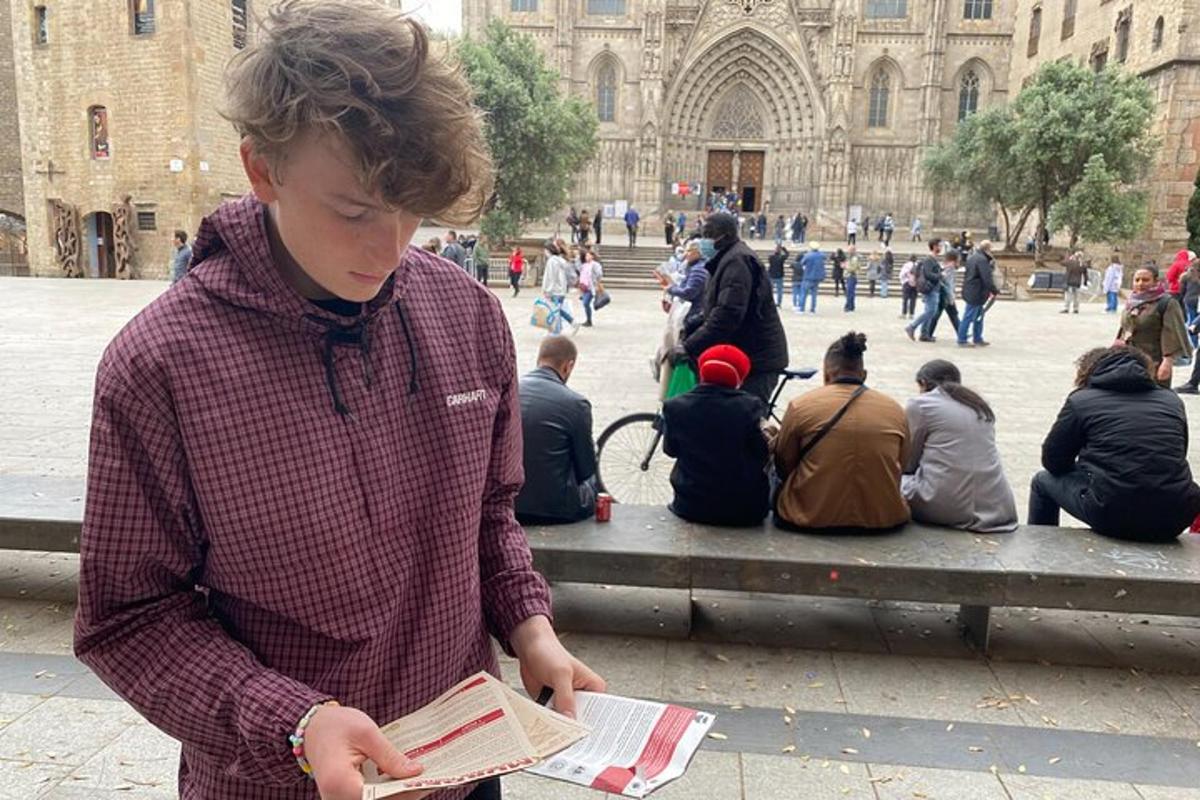un noi jove llegint un llibre davant d'un edifici