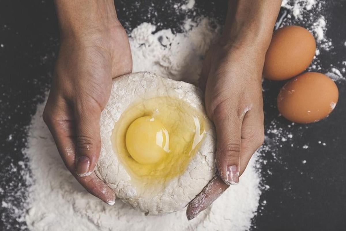 seseorang sedang memegang telur di tepung