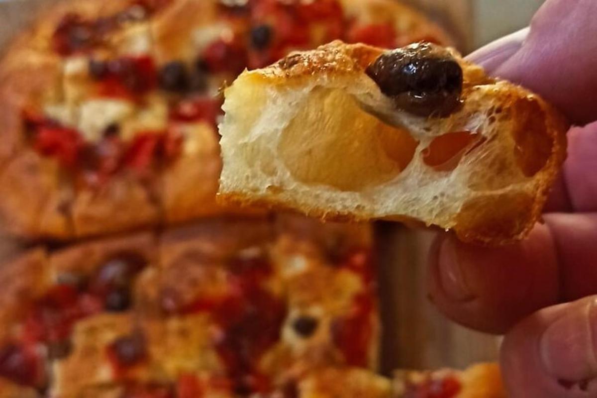 seseorang sedang memegang sepotong pizza