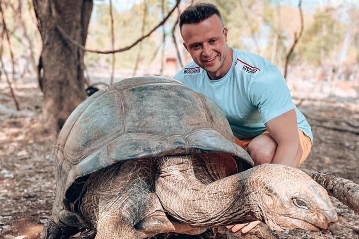 ein Mann sitzt neben einer großen Schildkröte
