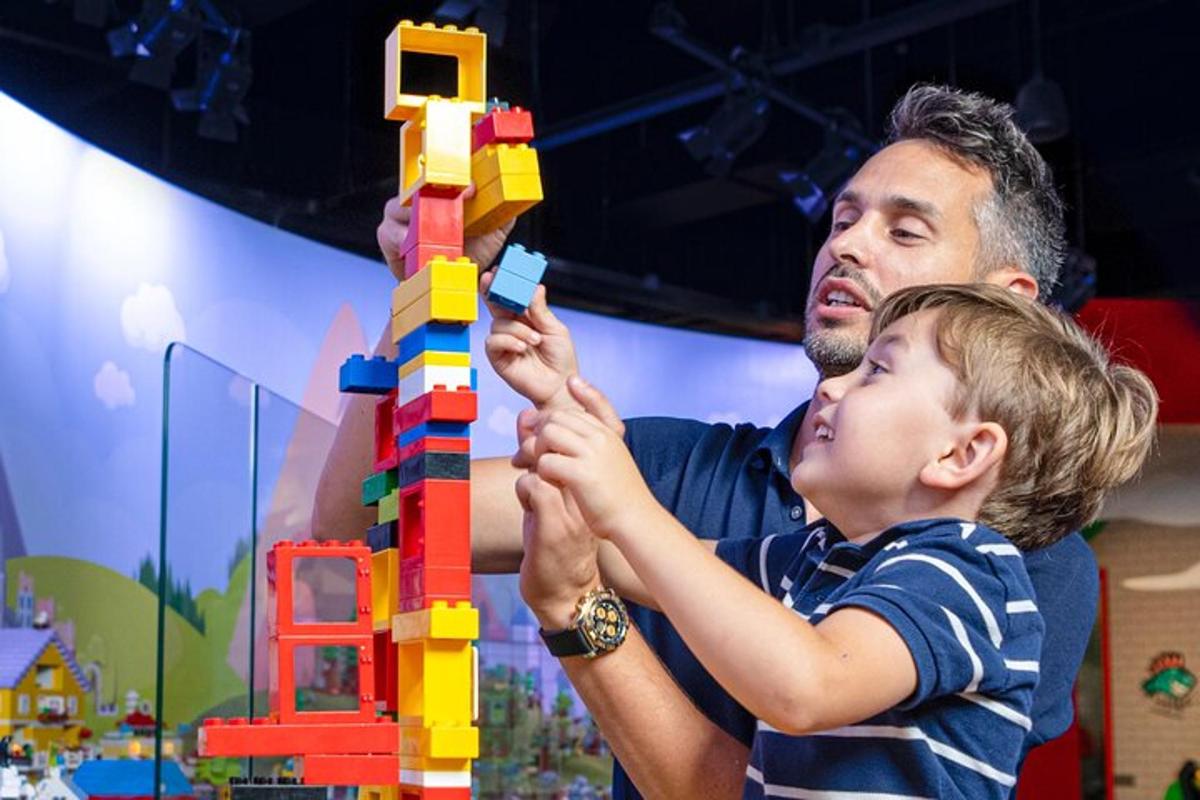 a man and a child playing with a lego tower