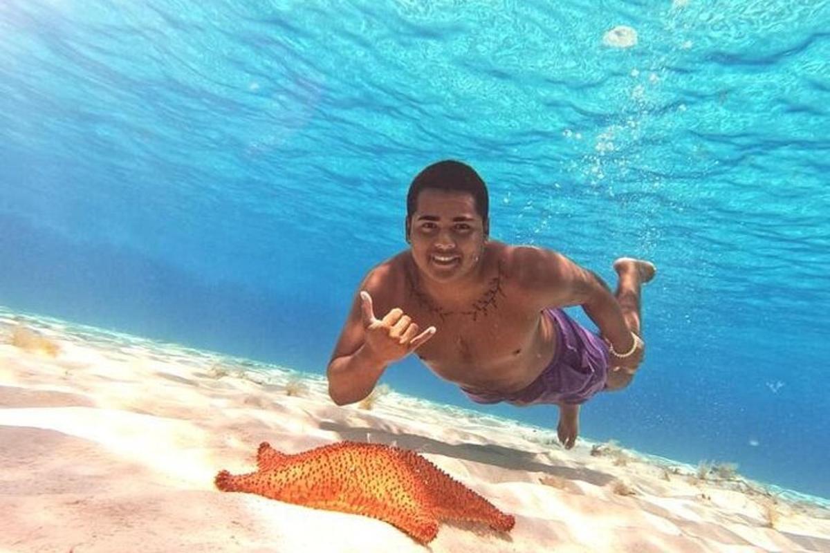 un hombre en el agua junto a una estrella de mar