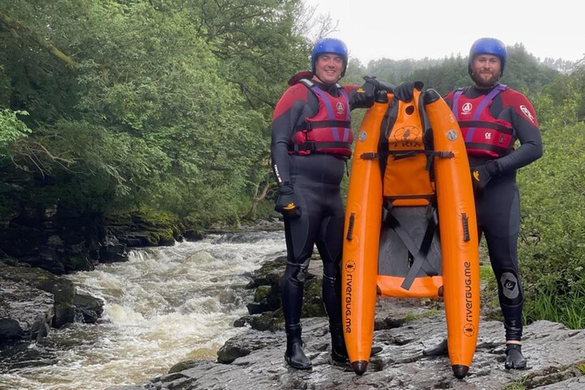 two people standing on a river with a raft