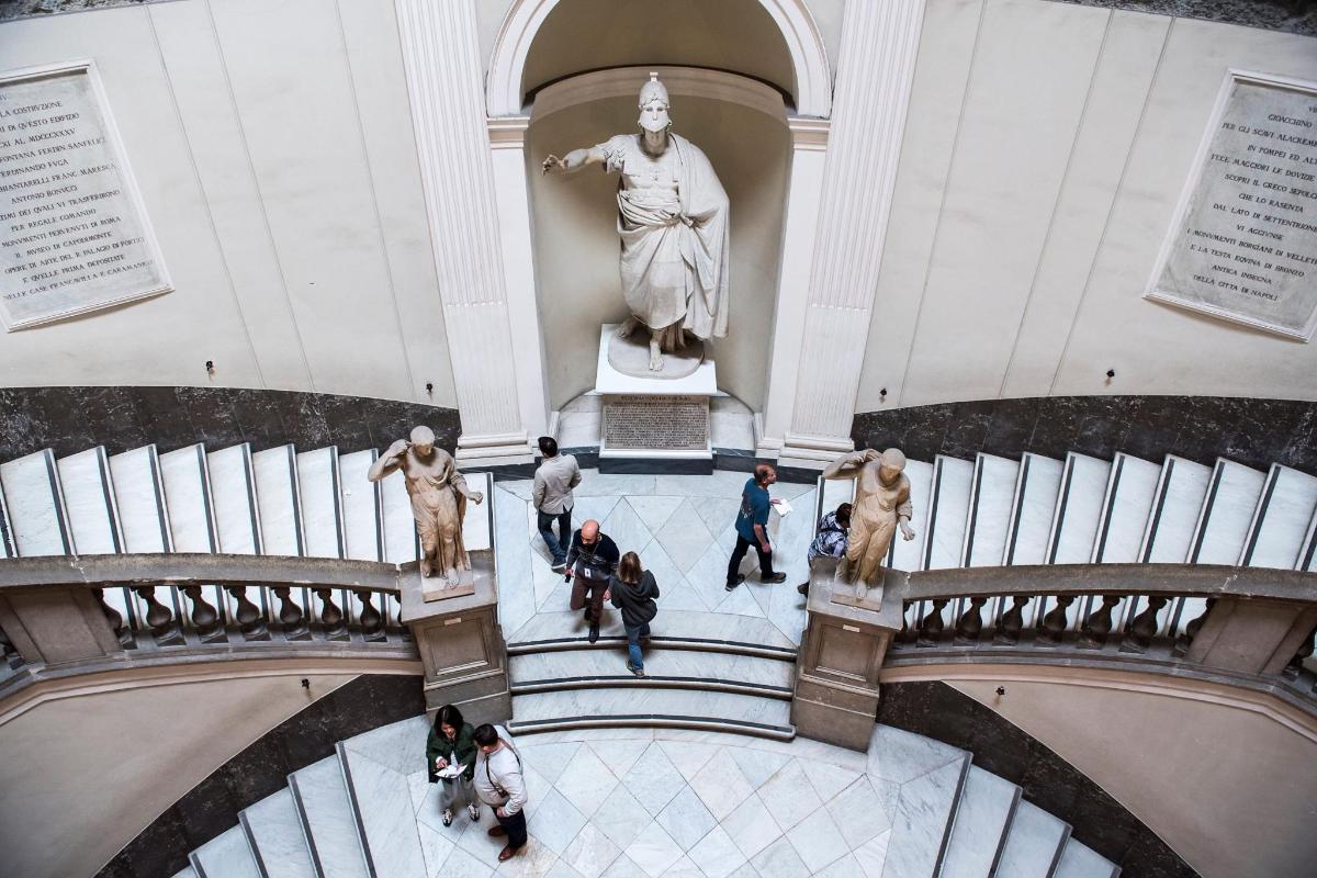 a group of people walking in a museum with a statue
