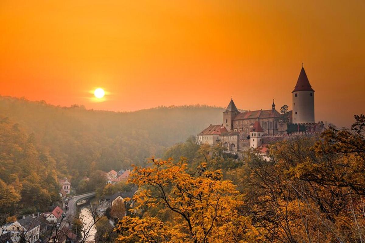 Un castillo en una colina con la puesta de sol al fondo