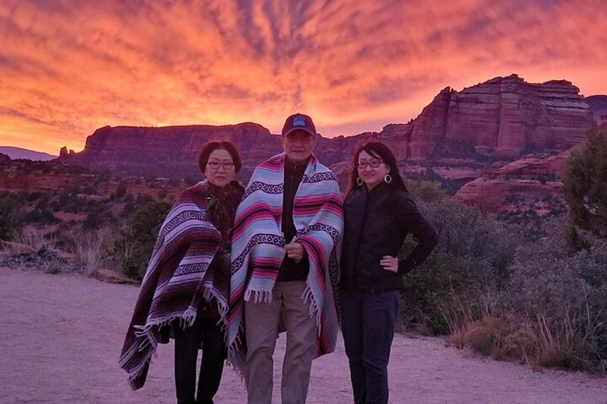um grupo de três pessoas em pé no deserto ao pôr do sol