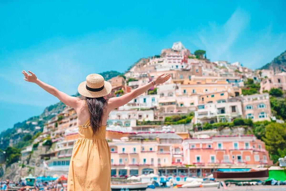 žena v klobouku stojící na pláži a dívající se na Positano