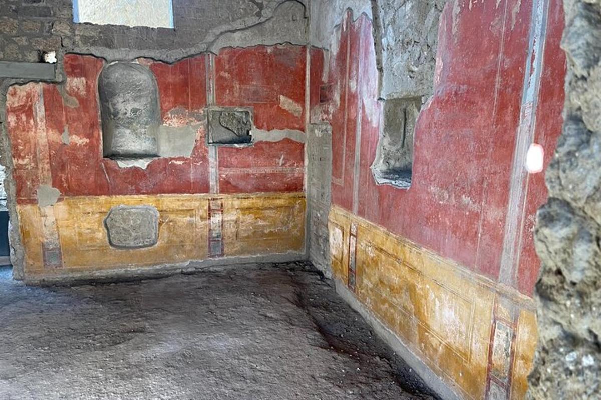 une vieille pièce avec un mur rouge et une porte en bois