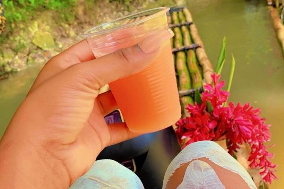 một người đang cầm một cốc nhựa đựng chất lỏng màu cam