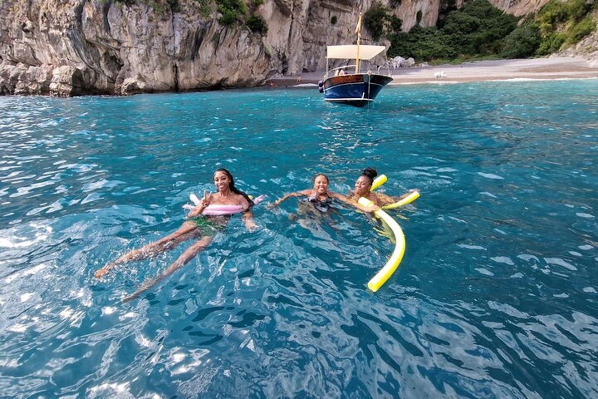 three people swimming in the water with a boat