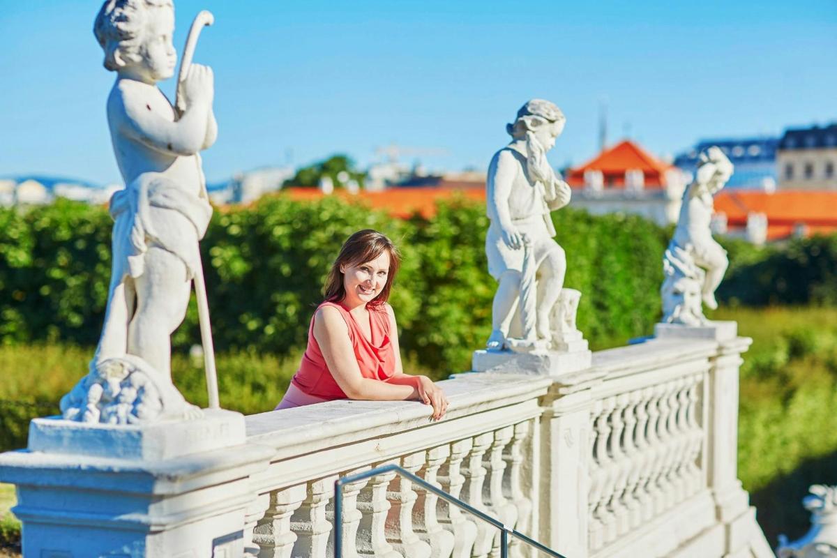 một người phụ nữ ngồi trên cầu với những bức tượng