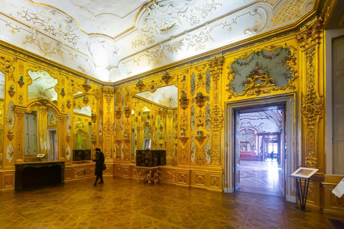 a person walking through a room with ornate gold walls