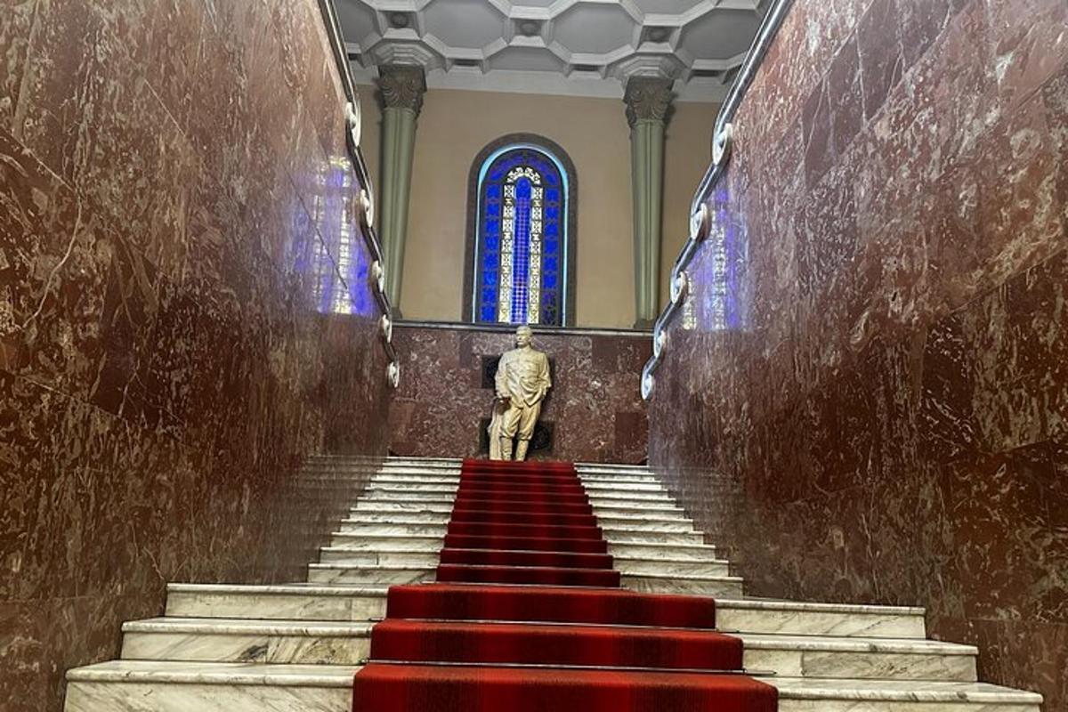 een trap in een kerk met een standbeeld en glas-in-loodramen