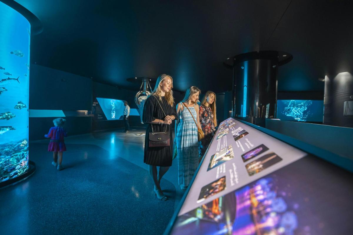 Un grupo de mujeres de pie junto a una mesa en un museo.