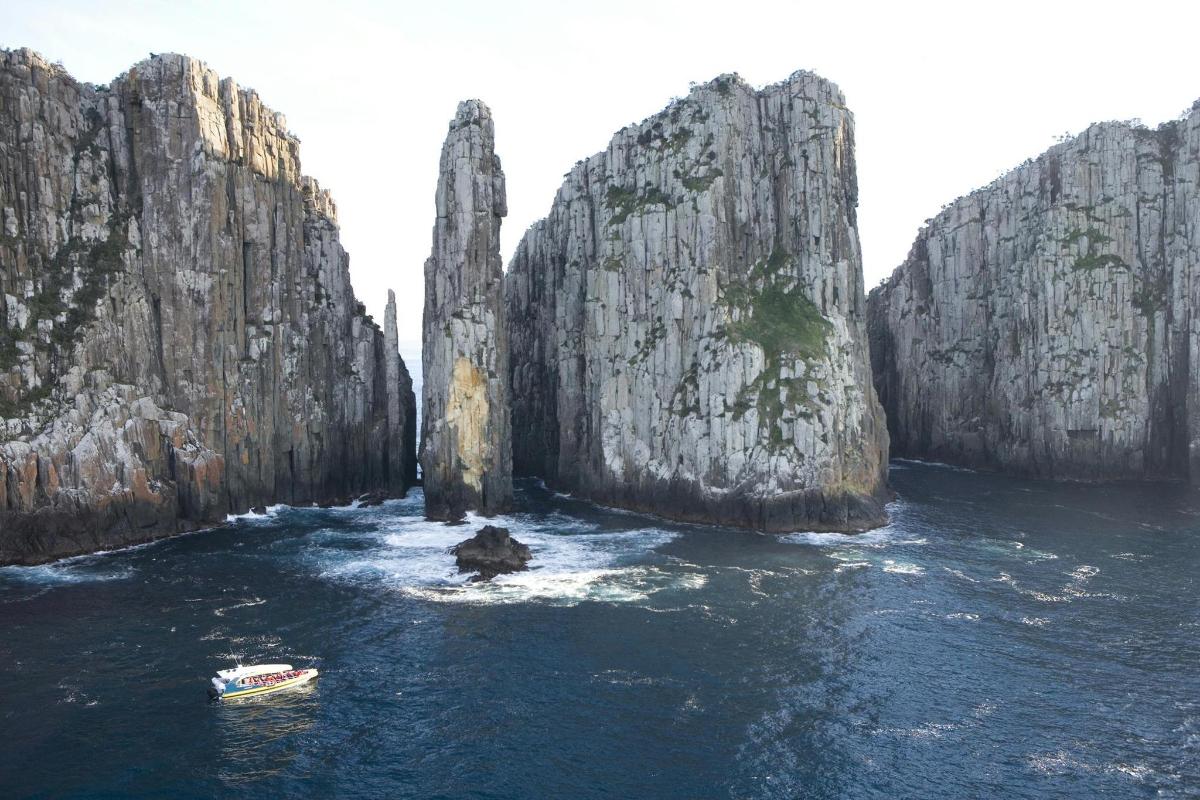 a boat in the water between two large rocky cliffs