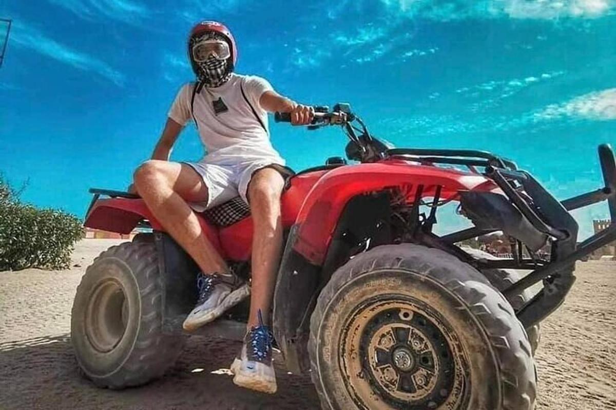 muž sedící na červené čtyřkolce
