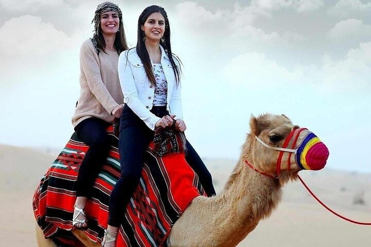 duas meninas andando de camelo no deserto