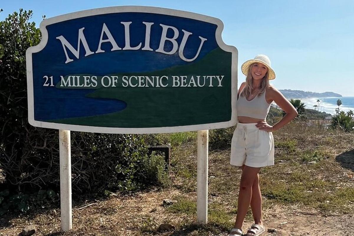 a woman in a hat standing next to a sign