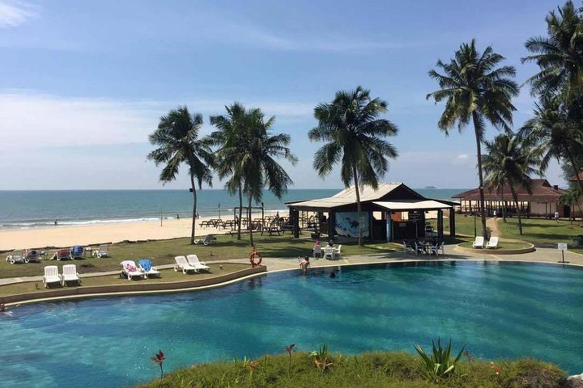 a large swimming pool next to a beach with palm trees