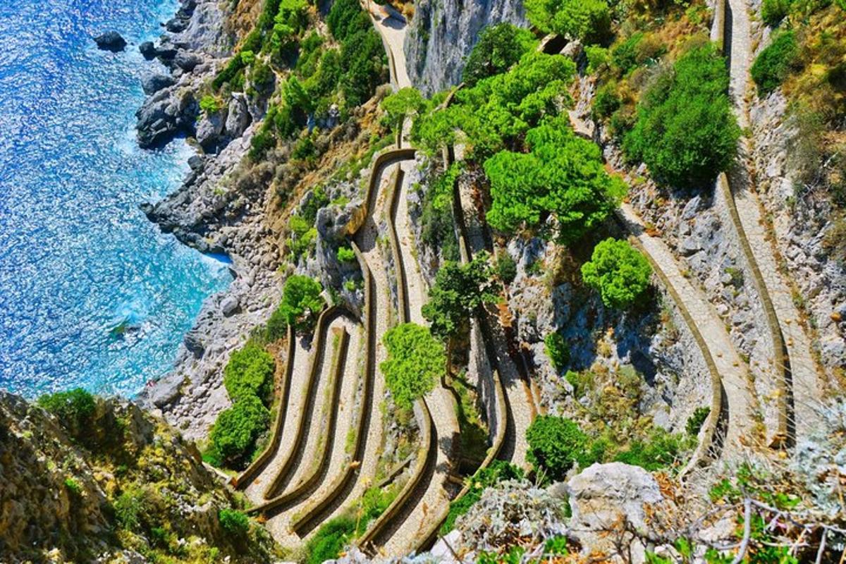a winding road on the side of a mountain next to the ocean