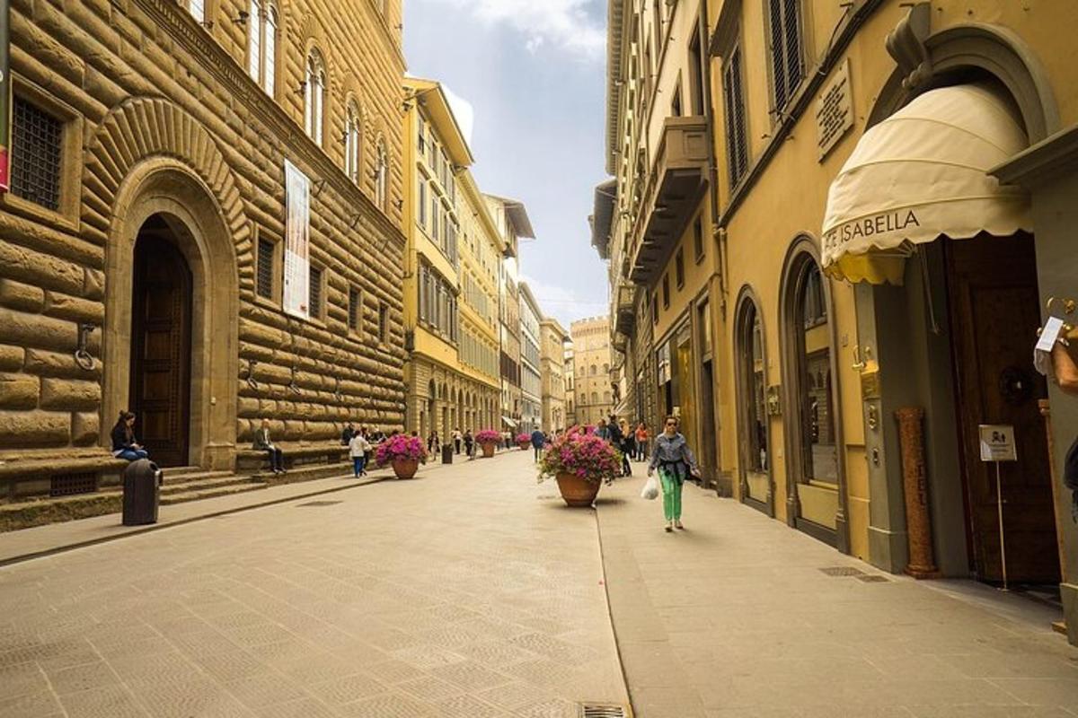 особа која хода улицом са цвећем у саксијама